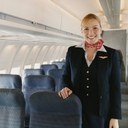 a woman in a uniform standing in an airplane