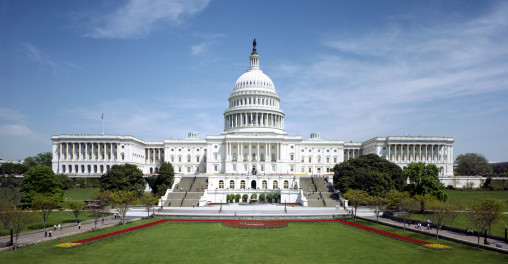 a white building with a dome and a lawn with United States Capitol in the background