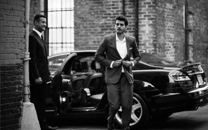 a man in a suit walking by a car