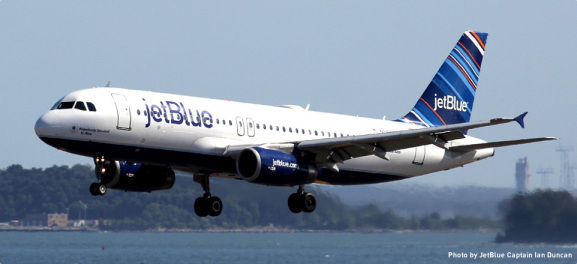 a jet blue airplane flying over water