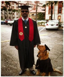 a man in a graduation gown and cap with a dog