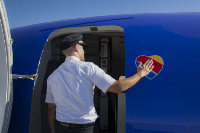 a man in a uniform opening a door of a plane